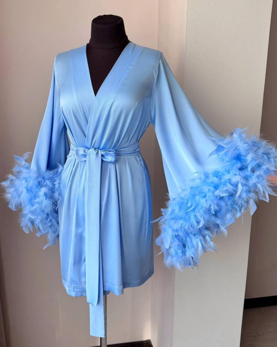 a blue robe with feathers on a mannequin