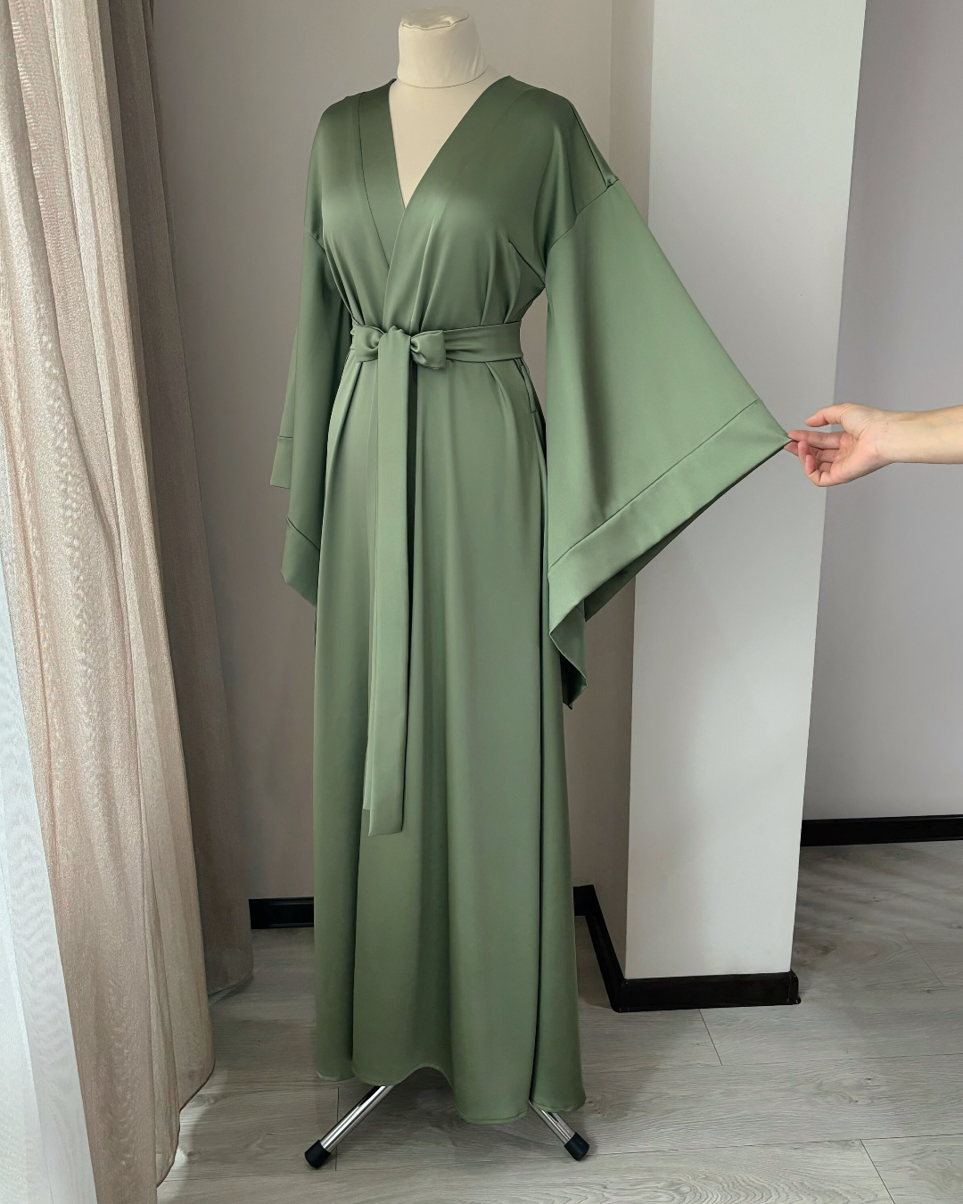 a green robe is being held up by a mannequin