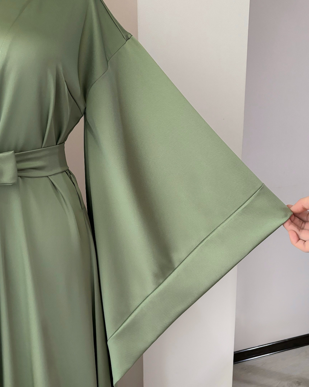 a woman in a green dress is holding a piece of fabric