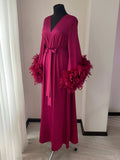 A long, burgundy-colored robe with feather accents, displayed on a mannequin.