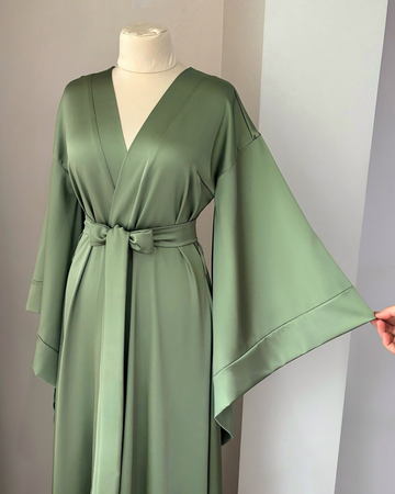 a green robe is being held up by a mannequin