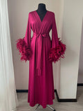 A long, pink robe with feather accents displayed on a mannequin.
