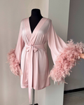 a pink robe with feathers on a mannequin