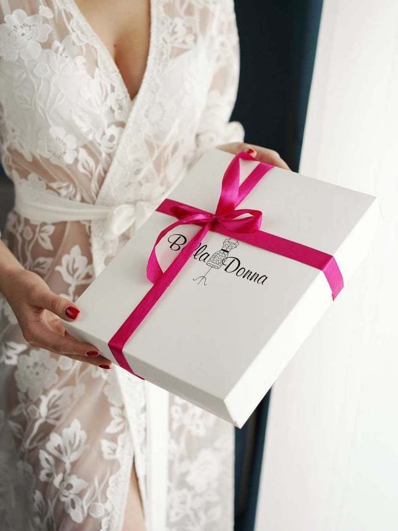 a woman holding a white box with a pink ribbon